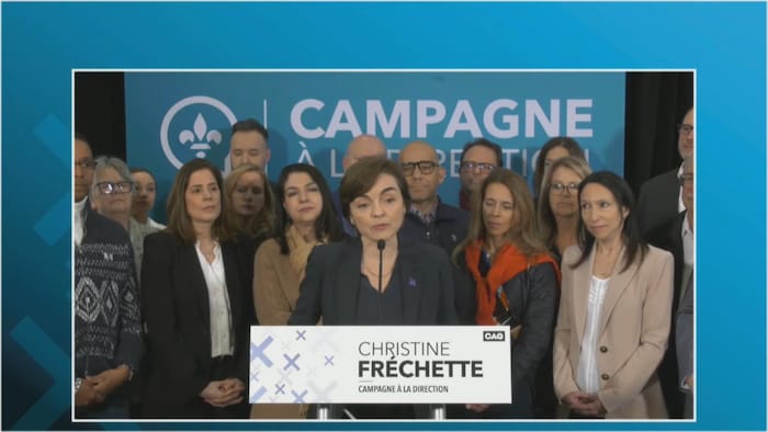 Christine Fréchette derrière un lutrin répond aux questions entourée d'élus qui la soutiennent.