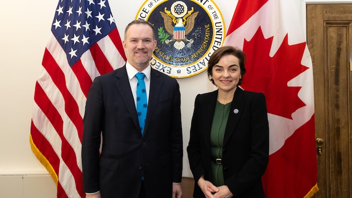 Christine Fréchette et Jamieson Greer devant des drapeaux canadiens et américains. 