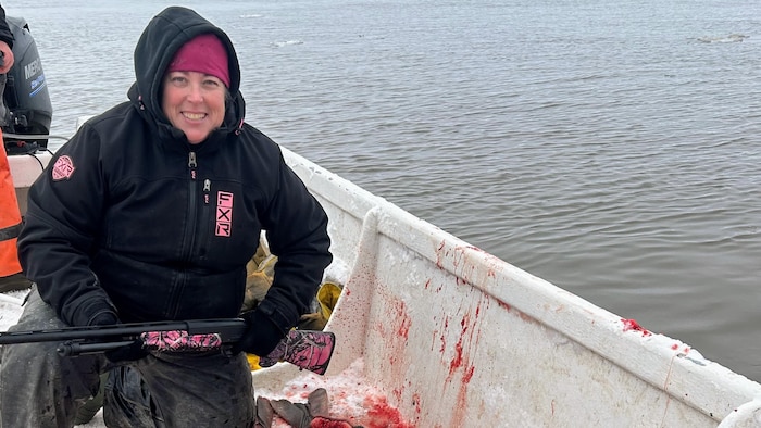 Christine Kelly sur un bateau, avec une carabine, du sang en arrière-plan.