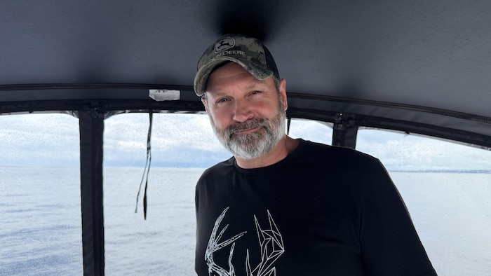 Un homme avec une casquette dans un bateau sur un lac. 