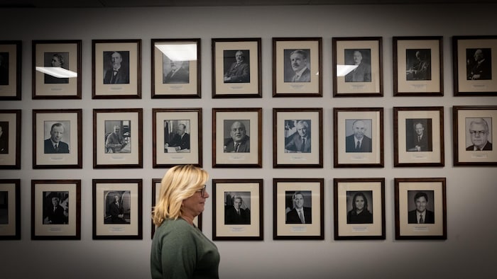 Une femme passe devant une galerie de portraits des anciens ministres des Finances du Canada.