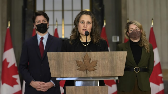 Chrystia Freeland prend la parole entourée de Justin Trudeau et de Mélanie Joly.