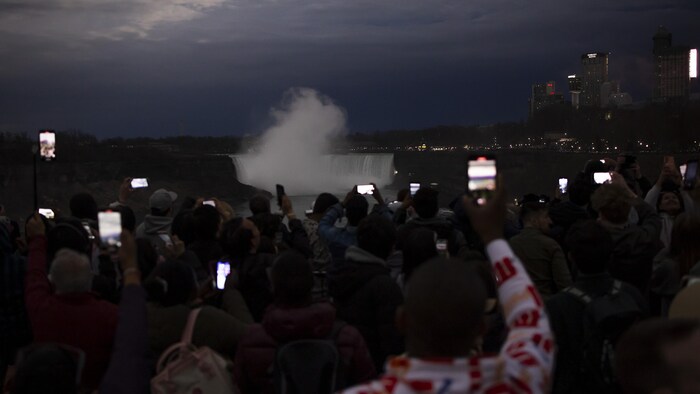 Des personnes avec leur téléphone pointé vers le ciel et les chutes Niagara en fond