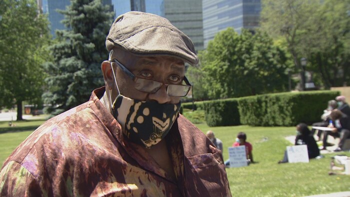 Un homme noir, petit béret, masque en tissu et lunettes