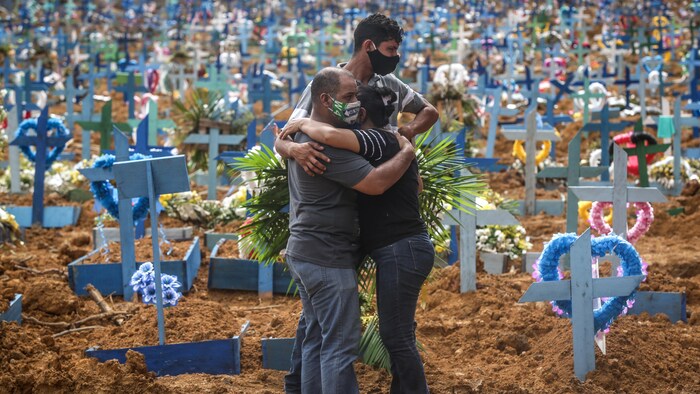 Des gens s'étreignent dans un cimetière.