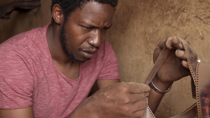 Un homme africain tient dans ses mains une pellicule de cinéma.