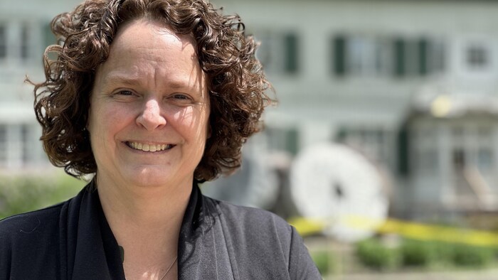 Cindy Desrochers sourit à l'extérieur dans un décor flouté.
