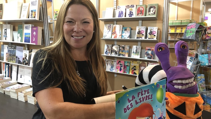 Une femme devant un livre pour enfant et un jouet en peluche.