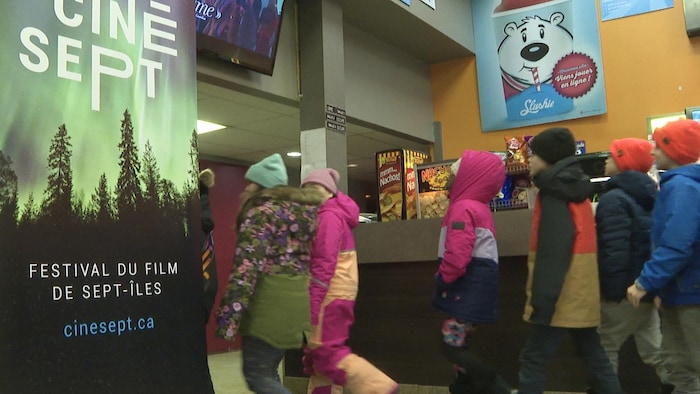 Des enfants arrivent en grand nombre au cinéma.