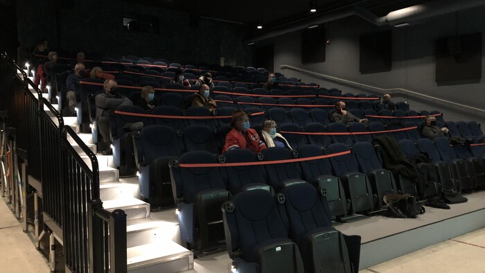 Plus d'une dizaine de spectateurs sont dispersés dans une salle de cinéma.