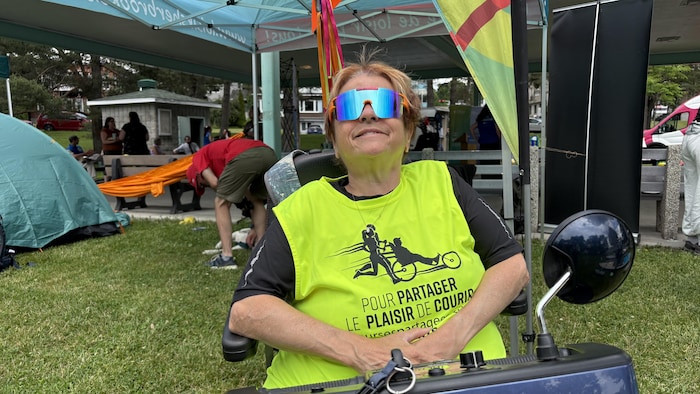 Collette Jean, souriante, aux commandes d'un triporteur.