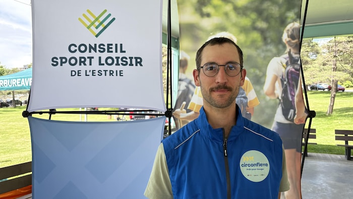 Oscar Dupouy, devant une affiche du Conseil Sport Loisir de l'Estrie.