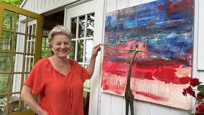 Nathalie Sanche devant sa sculpture. Il s'agit d'une silhouette masculine, les bras ouverts.