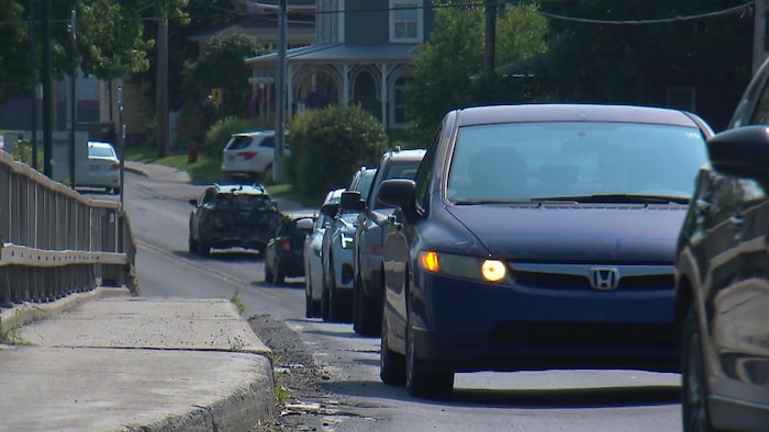 Des voitures circulent à la queue-leu-leu sur une route provinciale. 