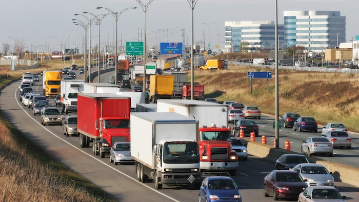 Des camions et des voitures roulent sur une autoroute. 