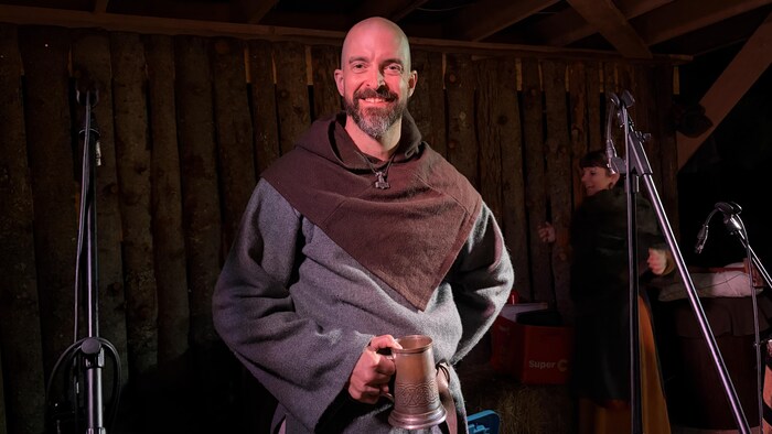 Maxime Poirier en habits d'époque, chopine à la main, souriant sur la scène du spectacle Beltane.