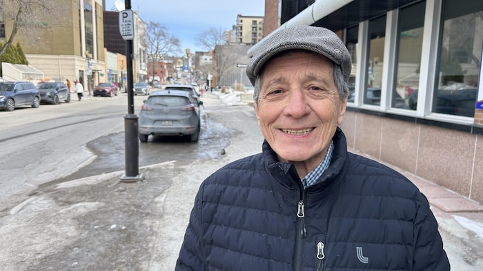 Un homme sourit sur la rue Racine, à Chicoutimi, pour la prise d'une photo. 