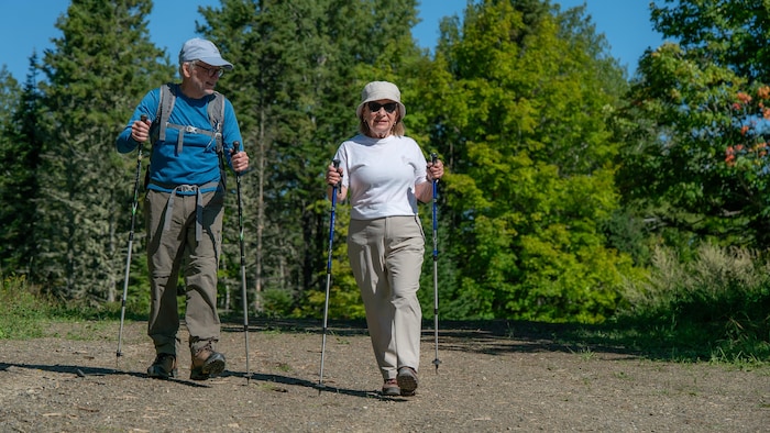 Portrait de Claire Pelletier avec des bâtons de randonnée, accompagnée d'un homme.