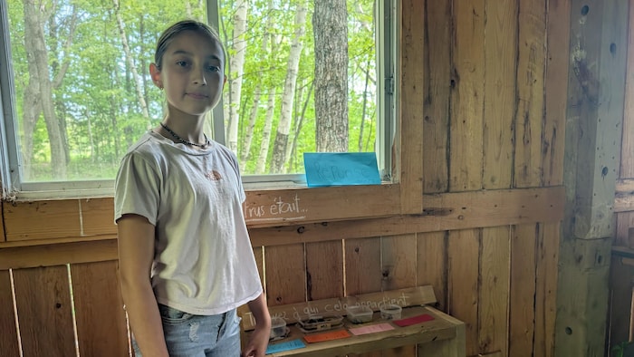 Une jeune fille dans une cabane en bois.