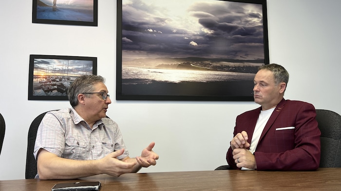 Claude Bélanger et Simon Deschênes assis à une table en pleine discussion.