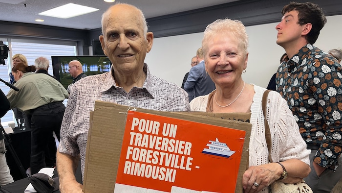 Claude Duguay et Gisèle Cassista tiennent une pancarte où est inscrit « Pour un traversier Forestville-Rimouski ».