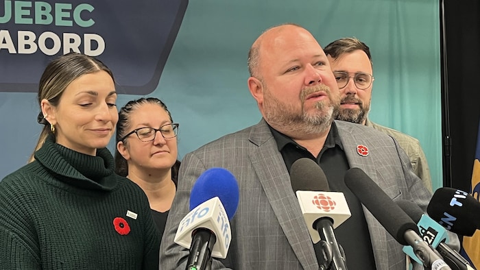Claude Villeneuve donne un point de presse entouré de membres de son équipe.
