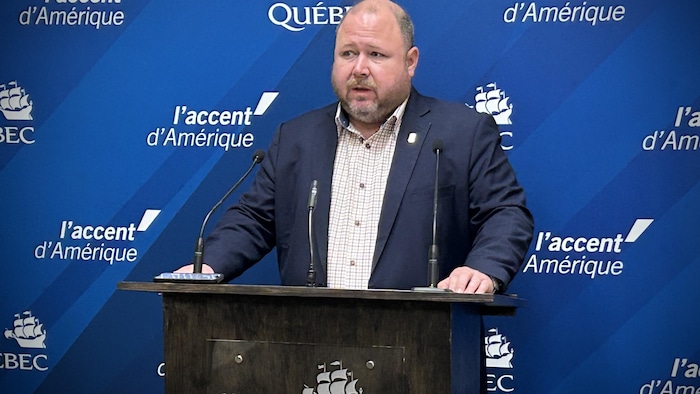 Claude Villeneuve derrière un lutrin de la Ville de Québec.
