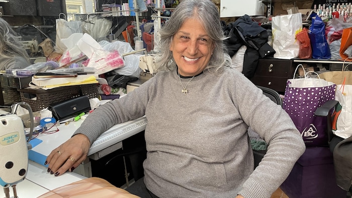 Une femme souriante derrière sa machine à coudre.