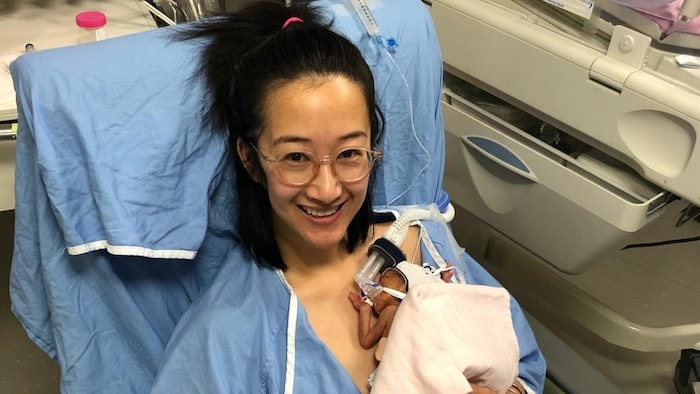 Elle tient son bébé en jaquette d'hôpital.