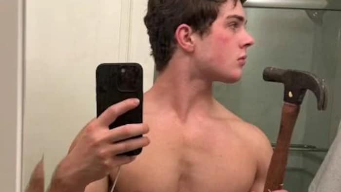 Clavicular se prend en photo devant un miroir en tenant un marteau.