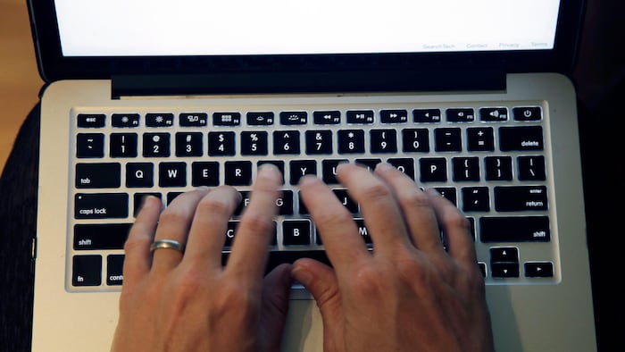 Des doigts sur le clavier d'un ordinateur portable.