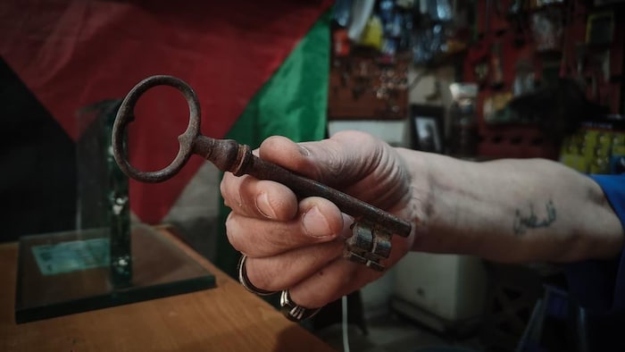 La main d'un homme qui tient une clé ancienne.