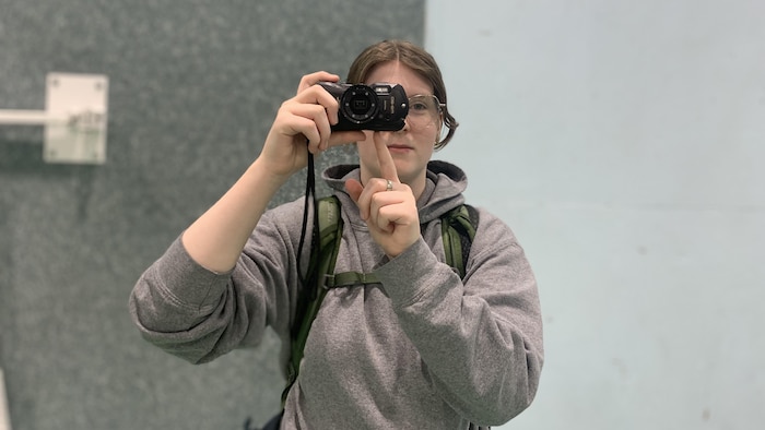 Une adolescente tente de prendre une photo avec son appareil photo. 
