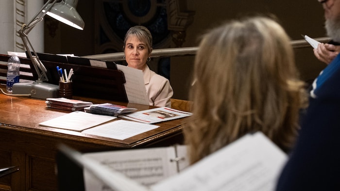 Une femme derrière un orgue regarde des choristes.
