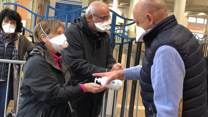 Une préposé propose du désinfectant à des clients.