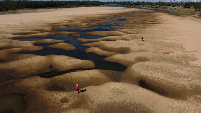 Aerial view of people walking along an almost dry arm of the Parana River, which water level reached a historic low, near Rosario, Santa Fe, Argentina, on August 22, 2021. - The Parana River, which runs through Brazil, Paraguay and Argentina, the tenth largest river basin in the world, has reached its lowest water level in over half a century and it is an enigma whether it is a natural cycle or a result of climate change, with uncertain long-term effects. (Photo by JUAN MABROMATA / AFP)