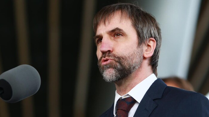 Le ministre en complet parle à un micro.