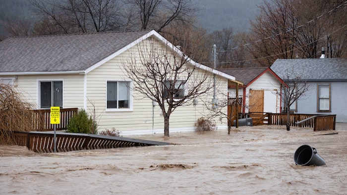 Une rivière recouvre une rue avec des maisons.
