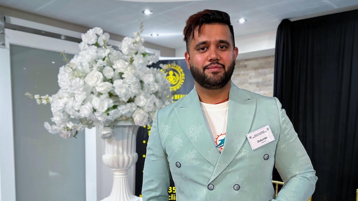 Le pharmacien Gaurav Sharma est debout devant un pot de fleurs.