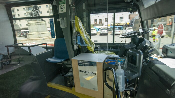 Un poste d'inscription avec plexiglas est installé devant le fauteuil du chauffeur d'un autobus converti de la STM.