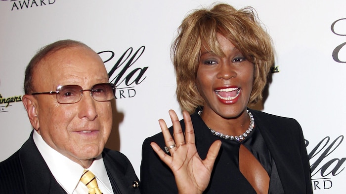 Le producteur et la chanteuse sourient sur le tapis rouge.