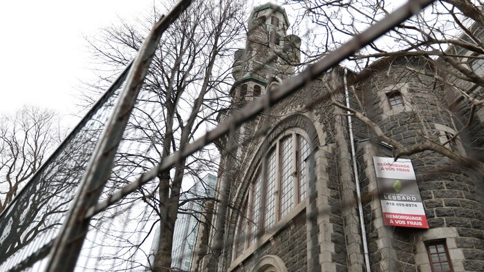 Une clôture métallique entoure une église en pierre.