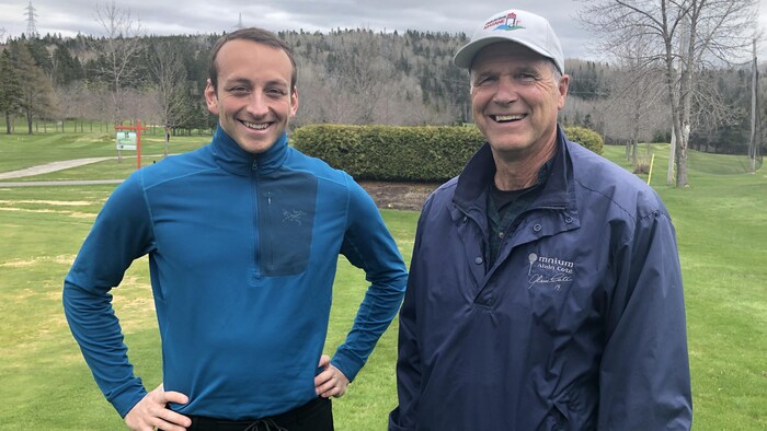 Deux hommes posent sur un terrain de golf.