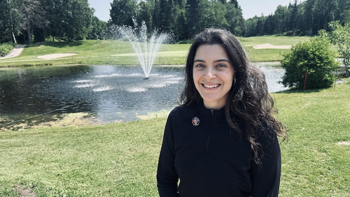 Une femme devant une fontaine sur un terrain de golf