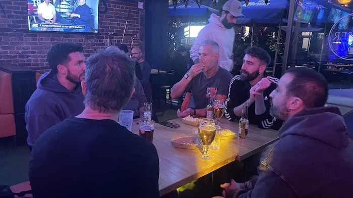 Un groupe d'homme est assis à une table et discute autour d'une bière.