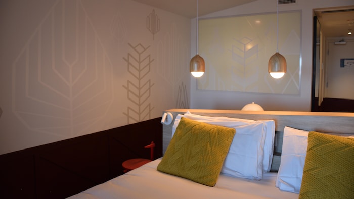 Un lit avec des coussins jaunes dans une chambre aux teintes de blanc et de rouge foncé