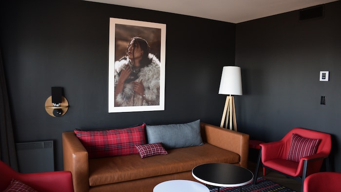 Un tableau avec une photo d'une femme au-dessus d'un sofa dans une petite pièce