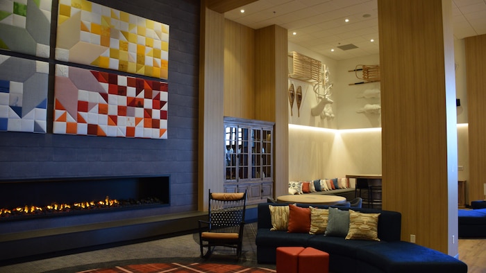 Le hall d'entrée de l'hôtel avec des couleurs chaudes et un foyer intégré dans le mur