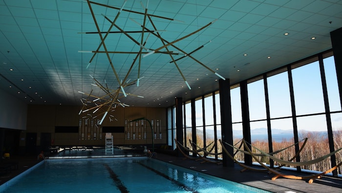 Une piscine avec des décorations en bois au plafond et des hamacs