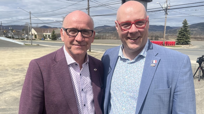 Deux hommes sourient à la caméra.